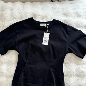 Svart t-shirt från Carin Wester - T-shirt med intagen midja, säljer pga är för stor