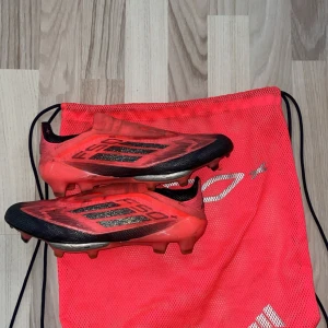 Adidas F50+ fotbollsskor - Skorna är bara lite smutsiga, inga skadefel på dom. Kan tvättas innan frakt.Säljer ett par röda Adidas F50 fotbollsskor med svarta och silvriga detaljer. Skorna har låg profil, platt sula med dobbar och är tillverkade i syntetmaterial. Perfekta för dig som vill ha snabba och lätta skor på planen. Original pris ca 3500kr! Priset går att diskuteras 