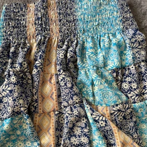 Mönstrad långkjol i blått och beige - Säljer en långkjol med smock i midjan och patchworkmönster i blått, ljusblått och beige. Kjolen har blommiga och geometriska mönster i olika sektioner och är gjord i ett lätt och mjukt bomullstyg. Perfekt för dig som gillar boho-stil och färgglada plagg. Otroligt skön material! Passar både storlek M & S.