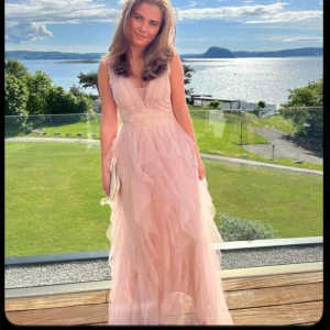 Ljusrosa långklänning med volanger och v-ringning - Säljer denna jätte fina fest/balklänning. Säljer då den inte passade mig. Ny utan prislapp, nypris ligger på ca 3000kr. Storlek S💕