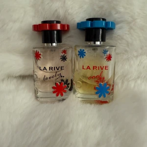 La Rive Lovely & Cool parfym duo - Två flaskor parfym från La Rive: Lovely och Cool. Båda flaskorna är dekorerade med färgglada blommor och har runda lock, ett rött och ett blått. Flaskorna är genomskinliga och har sprayfunktion. Perfekt för dig som gillar lekfull design och fräscha dofter.