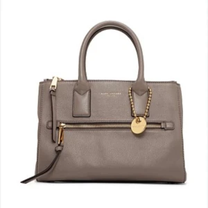 Taupe handväska från Marc Jacobs - Orginal Marc Jacobs läderväska, komplett med avtagbar axelräm som tillkommer, även dustbag. Invändigt finns flera fack för smart förvaring. Perfekt för dig som vill ha en klassisk och snygg accessoar. Använd väldigt lite, i fint skick. Lergrå färg, 