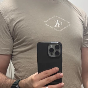 Beige t-shirt från Calvin Klein Jeans - Säljer en beige t-shirt från Calvin Klein Jeans med liten vit logga tryckt på bröstet. Klassisk passform och rund halsringning. Perfekt för en stilren och enkel look.