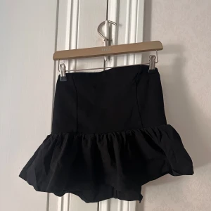 Svart bandeautopp  - Supersnygg svart bandeau topp som är tajt upptill som sedan övergår till volang, knappt använd men så i superfint skick!💗