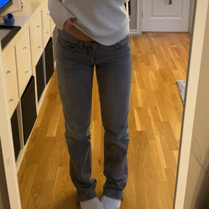 Grå jeansbyxor - Säljer ett par klassiska grå jeansbyxor med ”baggy” passform. De är lågmidjade och har knappar som man knäpper hela vägen upp istället för dragkedja.  