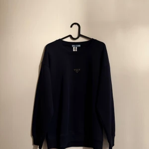Prada sweatshirt  - Tjena! Säljer denna Prada sweatshirt då den inte passade mig. Den är mörkblå i färgen (nästan svart) riktigt skön och stilren!                                              ⚠️‼️BYTEN ÄR INTRESSANT‼️⚠️