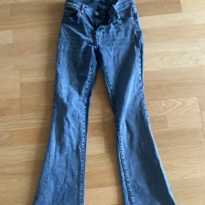 Grå bootcut jeans från Gina Tricot  - Snygga grå jeans med bootcut passform och klassiska fem fickor. Jeansen har låg midja och stängs med dragkedja och knapp. Perfekta för dig som gillar en retroinspirerad look med lite utsvängda ben.