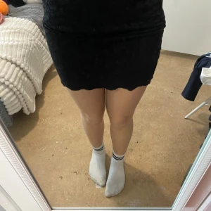 Svart kortkjol 50kr/st - En svart kortkjol med enkel design och rak passform. Kjolen är figurnära och passar perfekt till olika stilar. Materialet känns mjukt och stretchigt.