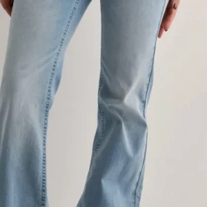Bootcut ljusblå jeans med broderi - Snygga ljusblå bootcut jeans med broderad detalj i rött och vitt på bakfickorna. Jeansen har klassisk femficksdesign och är tillverkade i mjukt denimtyg. Perfekta för dig som gillar en retrovibe och vill sticka ut lite extra.