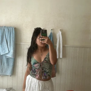 Färgglad croppad linnetopp med snörning - Säljer en superfin croppad linnetopp med smala axelband och v-ringning. Perfekt för varma dagar och ger en trendig vibe. Använd ca 3 gånger men är i perfekt kvalitet 🤩 Köpt från Pull&Bear.