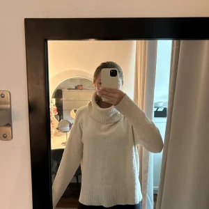 Beige polotröja med bred krage - Mysig beige polotröja med bred, ribbstickad krage och långa ärmar. Tröjan har en avslappnad passform och ribbade muddar vid ärmslut och nederkant. Perfekt för kyliga dagar och enkel att matcha med jeans eller leggings.