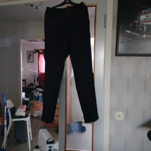 Svarta kostymbyxor Gina Tricot S - Svarta kostymbyxor från Gina Tricot i storlek S. Byxorna har en klassisk rak passform med midja och stängs med knapp och dragkedja. Perfekta till en snygg och clean look. Materialet känns mjukt och följsamt.