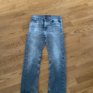 Replay grå jeans med raka ben Thad.strl w28 L30 - Snygga grå jeans från Replay med raka ben och klassisk femficksdesign. Jeansen har en tvättad look med ljusa partier och diskreta sömmar på bakfickorna. Perfekta för dig som gillar en avslappnad men stilren vibe.