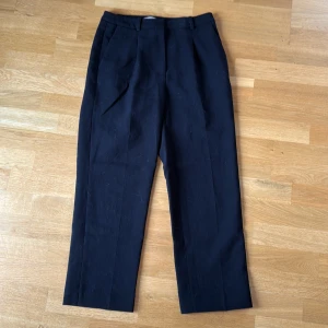 Svarta kostymbyxor med pressveck - Snygga svarta kostymbyxor med klassiska pressveck och hällor för bälte. Byxorna har rak passform och sidfickor, perfekta för en clean och stilren look. Materialet känns mjukt och har en lätt struktur. Använda men inga nopprar eller liknande. Från H&M i storlek 38, normal längd. Priset går att få ner vid snabb affär❤️ Köpte för 399kr inte använt så mycket då jag inte orkade sy upp dem