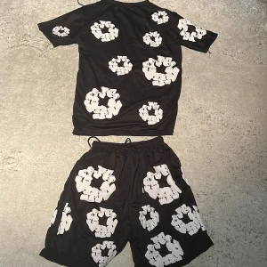 Svart t-shirt med vita tryck från Denim Goods - Svart t-shirt från Denim Goods i storlek S med unika vita grafiska tryck över hela plagget. T-shirten har klassisk passform och korta ärmar. Materialet känns lätt och passar perfekt till sommaren. Snygg och sticker ut med sitt coola mönster.