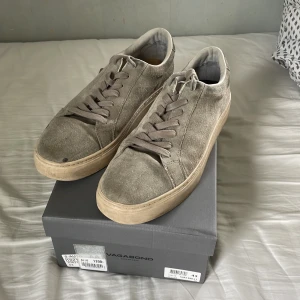 Grå mockasneakers från Vagabond - Snygga grå sneakers från Vagabond i mjuk mocka med klassisk låg profil och rund tå. Skorna har matchande grå snörning och en beige platt sula som ger en clean och stilren look. Perfekta för dig som gillar minimalistisk stil och neutrala färger. Kvitto och original låda är såklart med.