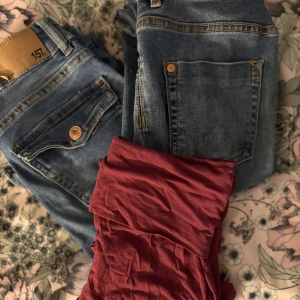 Två blå jeans & vinröda vida byxor - Säljer två par klassiska blå jeans med snygga detaljer och ut svägda ben, samt ett par vinröda vida byxor ut svägda,en liten fläck på röda byxor inget jag har tänkt på så mycket,Avänt Max 2 gånger 