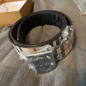 Bälte med Silvrig B logga  - Nu säljer jag mitt silvriga bälte för jag inte har användning då den inte passar min stil trodde den skulle göra det men det gjorde den inte så säljer den vidare i helt nytt skick innan den hinner smala damm här hemma pris kan diskuteras vid snabb och smidig affär Först till kvarn!