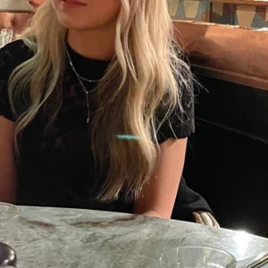 Svart spetstopp från Lindex - Supersöt svart topp från Lindex i genombruten spets med blommigt mönster. Toppen har korta ärmar och en figurnära passform. Perfekt för dig som gillar en feminin och stilren look.