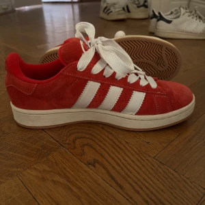 Röda Adidas Campus  - Snygga Adidas Campus sneakers i röd mocka med klassiska vita ränder och vit sula. De är storlek 42 2/3 men passar också mig som brukar ha 41-42 i skor. De är de bekvämaste skorna jag äger💕Ställ gärna frågor! 