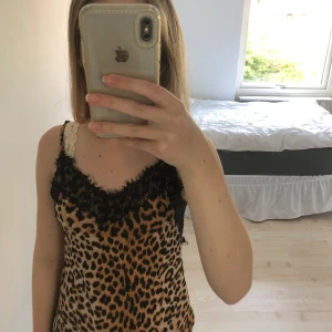 Leopardmönstrad linnetopp med spets - Snygg linnetopp med leopardmönster och tunna axelband. Toppen har svarta spetsdetaljer längs urringningen som ger en extra cool touch. 