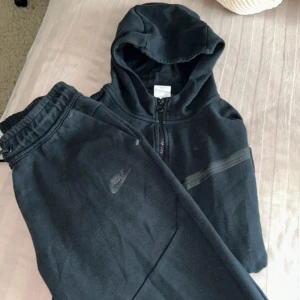 Nike tech fleece - Svarta Nike tech tracksuit i storlek XL för barn, passar dig som är runt 158-170cm lång. Denna tracksuit är använd fåtal gånger och har en enkel och clean look. Perfekta för chill eller träning, tillverkade i mjukt material för maximal komfort.