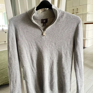 Half zip - Snygg grå ribbstickad tröja från H&M med half zip-dragkedja och hög krage. Slim fit-modell med långa ärmar, perfekt för lager-på-lager. Skön och stilren, funkar till många outfits.