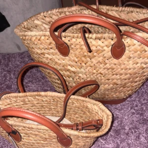 Stråväska med bruna skinnhandtag - Snygg och rymlig shoppingväska i flätat strå med bruna skinnhandtag och detaljer. Perfekt att slänga över axeln när du vill ha med dig allt du behöver. Naturlig beige färg och klassisk form som ger sommarkänsla.