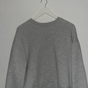 Grå basic sweatshirt - Enkel grå sweatshirt i klassisk modell med rund hals och långa ärmar från Gina Tricot . Tröjan har en loose passform och är tillverkad i mjuk bomullsmix, perfekt för chill dagar eller när du vill ha en clean look. Storlek M