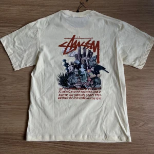 Gul Stüssy t-shirt med tryck - Snygg gul t-shirt från Stüssy med coolt konstnärligt tryck fram och stort grafiskt motiv på ryggen. 