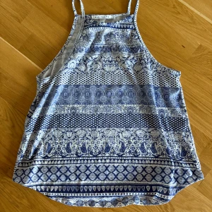 Blåvit mönstrad linnetopp NLY Trend - Supersnygg blåvit linnetopp från NLY Trend med tunna axelband och ett detaljerat mönster i olika blå nyanser. Toppen har en avslappnad passform och är perfekt för varma dagar. Mjuk och lätt i materialet, passar perfekt till jeans eller shorts.