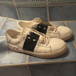 Valentino Garavani Open sneakers vit/svart - Snygga Valentino Garavani Open skor. Skorna är i bra skick men som man kan se kan de ha nått märke i fram vid tårna. Skorna går att få mycket vitare och rena då jag endast har torkat de med blött papper. Box kommer med. Priset går att diskutera lite grann