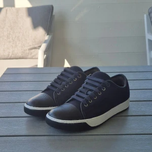 Lanvins marinblå - Snygga sneakers från Lanvin med marinblå ovandel i ull och svarta detaljer i skinn på tå och häl. Perfekt för dig som gillar stilrena och exklusiva sneakers med en twist. Storlek 6 som är 40 men lanvins har stor storlek skulle säga de sitter som 42 jag har 43 och får på mig de men de sitter tajt. Priset sitter inte hugget I sten. 