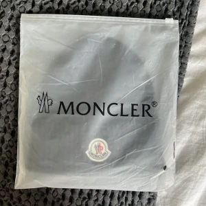 Svart Moncler Mössa - Helt Ny - Säljer en helt ny och oanvänd Moncler mössa i klassisk svart färg. Den är i originalskick med etiketter kvar, perfekt för både höst och vinter. Mössan är tillverkad i mjuk och varm ullblandning med det ikoniska Moncler-logotypen framtill.  💥 Äkta vara 🧵 Tjock och varm kvalitet 📦 Ny med tagg 📍 Unisex – passar både dam och herr  Nypris: ca 2000kr