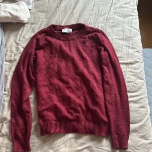 Vinröd stickad tröja från Vila - Vinröd stickad tröja från Vila i storlek XS. Klassisk modell med rund halsringning och ribbade muddar vid ärmslut och nederkant. Perfekt för lager-på-lager och enkel att matcha med jeans eller kjol.
