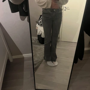 Grå bootcut jeans från Grunt - Snygga grå jeans från Grunt med bootcut passform. Jeansen har låg midja och är tillverkade i ett mjukt denimtyg som sitter skönt. Perfekta för dig som gillar en stilren look med lite retrovibe.