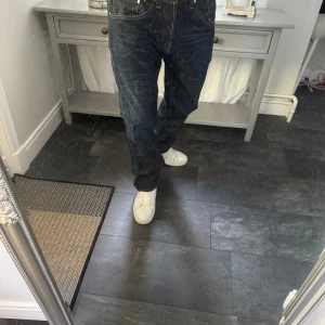Levi's 504 mörkblå jeans straight fit, vintage  - Mörkblå Levi's 504 jeans med klassisk straight fit och snygga slitningar. Jeansen har fem fickor, gylf med dragkedja och tydliga kontrastsömmar. Ikonisk läderpatch bak i midjan och Levi's röda etikett på bakfickan. Perfekta för en avslappnad streetstil.
