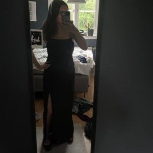 Svart långklänning med slits och öppen rygg - Supersnygg svart långklänning med smala axelband, öppen rygg med snörning. Bara använd 1 gång, så den är i väldigt bra skick. Tyvärr så har slitten gått upp en bit, men det är inget som man tänker på. Man skulle isf lätt kunna sy ihop den. Priset kan diskuteras💞kom privat för mer bilder 