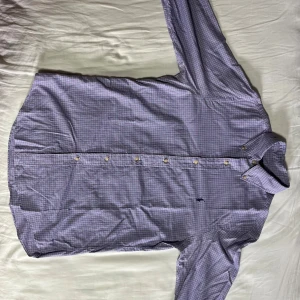 Rutig skjorta från Ralph Lauren - Snygg rutig skjorta från Ralph Lauren i blått, vinrött och beige. Klassisk button-down krage, broderad logga på bröstet och knäppning framtill. Skjortan är långärmad och tillverkad i mjuk bomull, perfekt för en stilren look. Helt oanvänd 