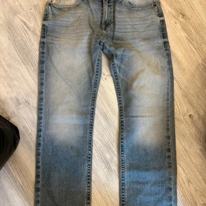 Ariat Slim Fit Straight Leg Jeans - Snygga ljusblå jeans från Ariat i modellen Slim Fit Straight Leg. Jeansen har klassisk femficksdesign, diskret tvättad look och raka ben. Tillverkade i stretchigt denim för extra komfort. Perfekta för dig som gillar en stilren och avslappnad vibe.