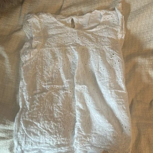 Topp med broderier - Jättesöt sommartopp med broderier och volang. Den är ifrån Grekland och har ingen lapp men passar en XS-M💕 Använd en gång och är i jättebra skick !!