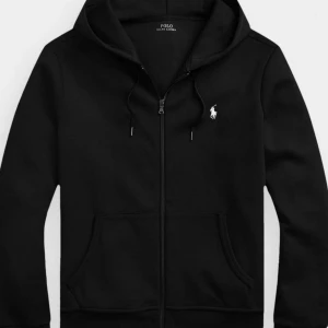 Helt ny Svart hoodie från Polo Ralph Lauren - Snygg svart hoodie från Polo Ralph Lauren med dragkedja och klassisk logga på bröstet. Perfekt för en avslappnad stil. Den har långa ärmar och en praktisk huva med snörning. Kan skickas och fraktas använd ca 2 veckor