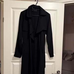 Svart trenchcoat - Tunn svart trenchcoat med långa ärmar och klassisk krage. 