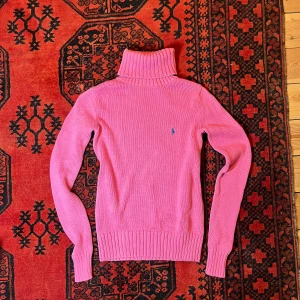 Rosa polotröja från Ralph Lauren Sport - Säljer en snygg rosa polotröja från Ralph Lauren Sport i 100% bomull. Tröjan har en klassisk polokrage och ett broderat blått märke på bröstet. Perfekt för kyligare dagar!