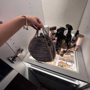 Grå stickad handväska med kedja - Säljer min snygg och trendiga grå/beigha stickade handväskan med en elegant guldig kedja som axelrem. Super snygg till sommaren men fick inte användning för den, så den är knappt använd. Nypris 490kr 