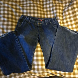 Blå lågmidjade bootcut jeans från Ché - Säljer ett par  blå lågmidjade bootcut jeans från Ché. Lite unika utan bakfickor. Har en mörkblå färg och är tillverkade i slitstark denim. Säljer eftersom de var för små för mig. Midjemått: 36cm Innerbenslängd: 78cm Skriv gärna om du har någon fråga.💞