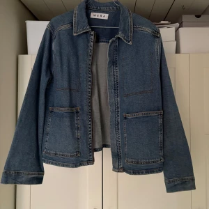 Blå jeansjacka från Wera - Snygg blå jeansjacka från Wera med klassisk design. Jackan har långa ärmar och två stora fickor framtill. Perfekt för en avslappnad stil. Den är i storlek 44 så den blir oversized på mig