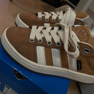 Bruna Adidas Campus sneakers - Snygga bruna Adidas Campus sneakers med vita detaljer och klassiska tre ränder på sidan. Använda 2 gånger. Kartong medföljer🤎