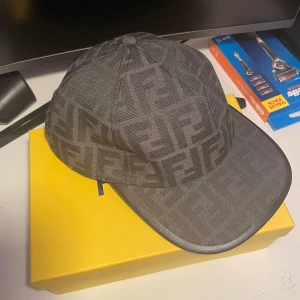 Fendi keps - Helt ny snygg svart keps från Fendi med deras ikoniska logotypmönster. Kepsen har en justerbar rem baktill för perfekt passform. Perfekt för att ge din outfit en lyxig touch. Pris går absolut att diskuteras 