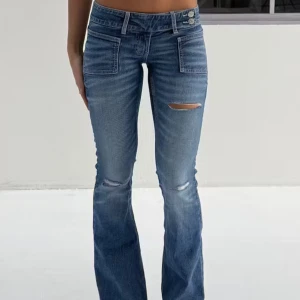 Blå jeans Gina  - Snygga blå jeans från Gina YOUNG +14 år med flare och slitningar på låret. De har en låg midja och dubbla knappar i midjan för extra stil. Storlek M  (HELT SLUTSÅLDA) helt nya, aldrig använDa